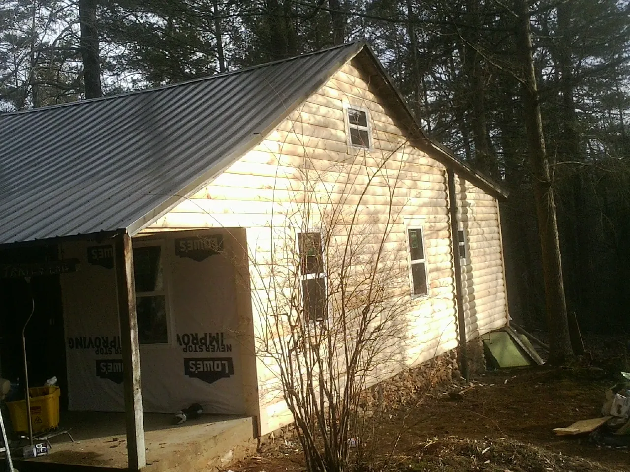 Log siding gable end under a dark metal roof edge in Allenton