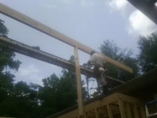 Carpenter setting a ridge beam over a new addition frame — Ice Dam Removal by Roofing Brothers in Allenton