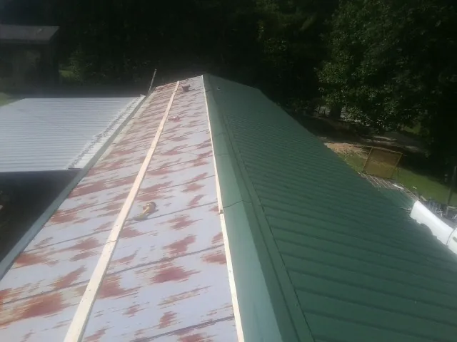 Old rusted panels beside newly installed green metal roofing — Wind Damage Roof Repair by Roofing Brothers in Allenton