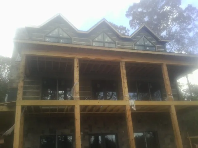 Dormers and porch framing on a large log home under construction — Roof Coating work by our crew in Allenton
