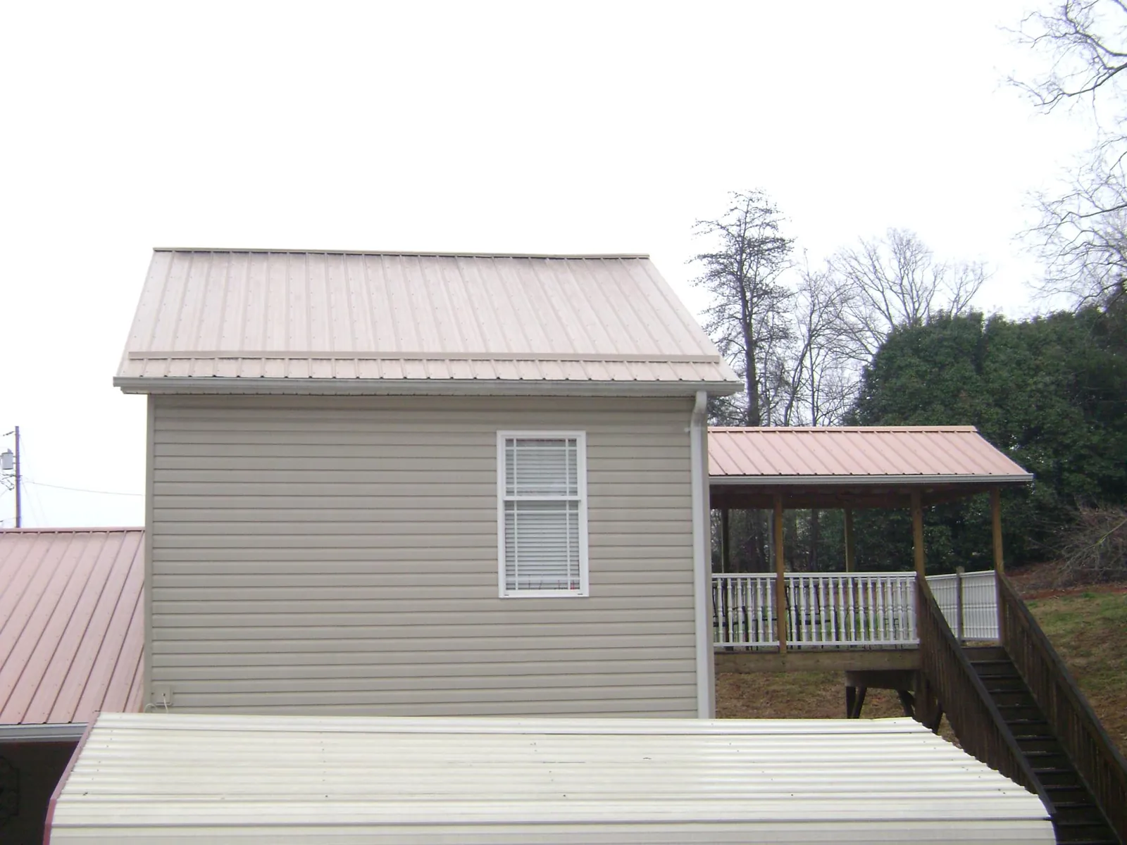 Tan metal roofs on a two story addition and attached porch, from a Roof Replacement job in Allenton